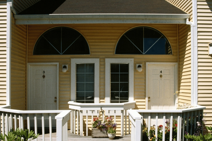 yellow multi-family home with two white front doors to each unit